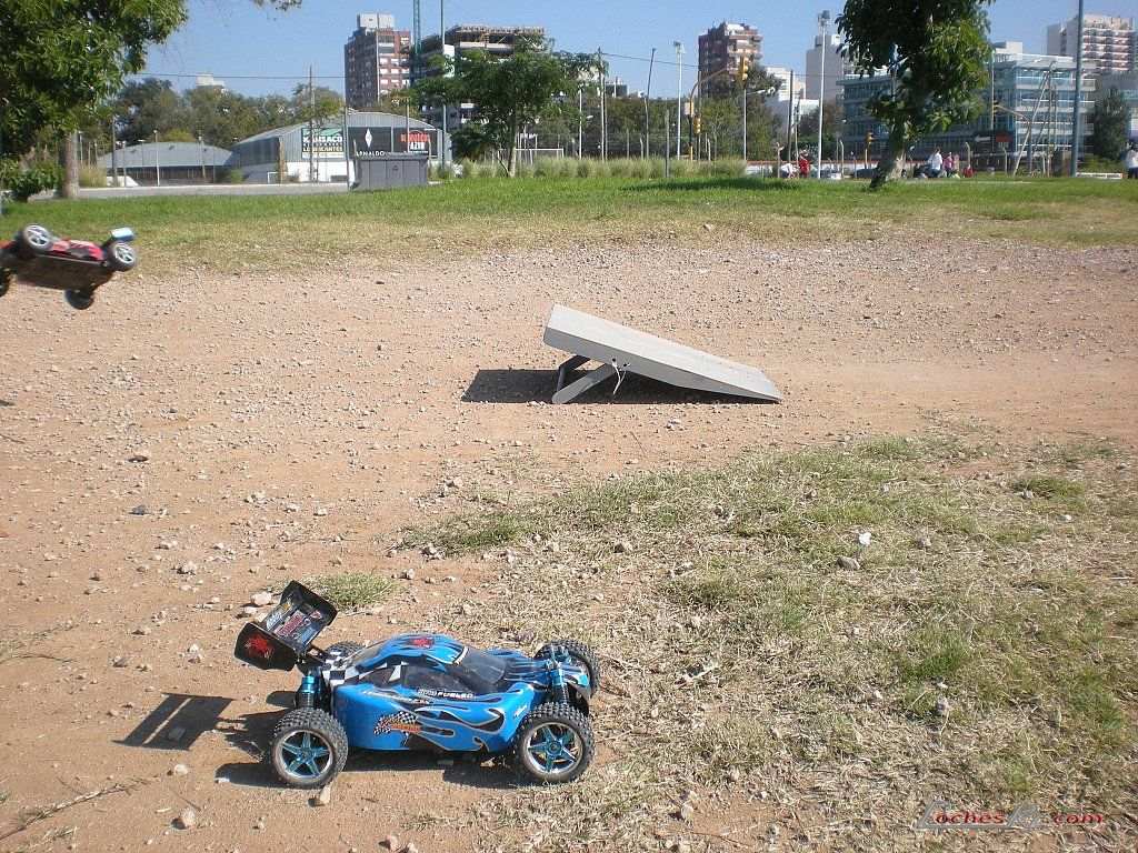 Buggy azul de radiocontrol rodando hacia una rampa de tierra