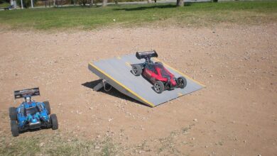 Dos buggies de radiocontrol junto a una rampa de saltos en un descampado