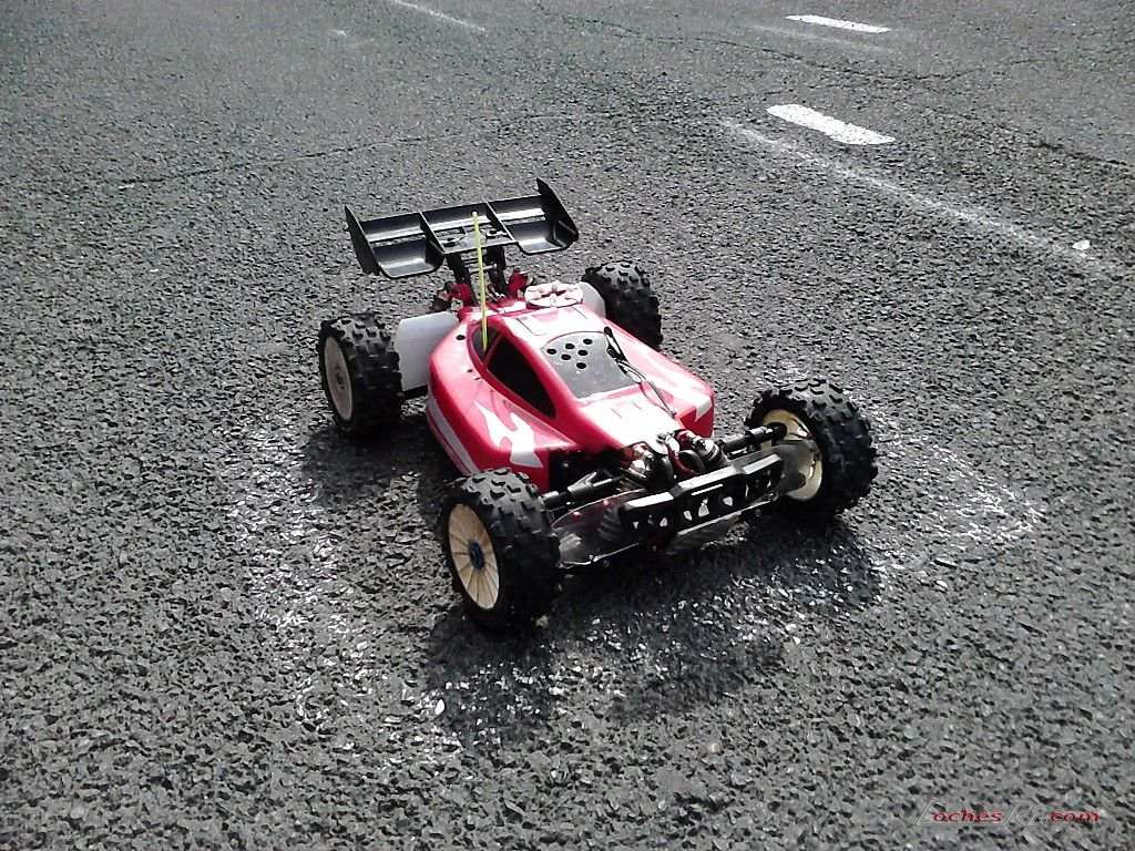 Buggy de radiocontrol con la carrocería pintada de llamas en rojo y blanco, rodando sobre asfalto