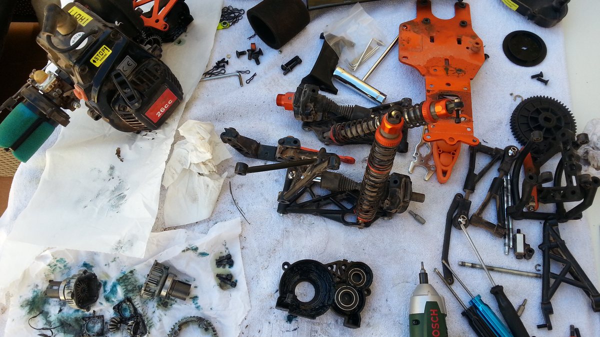 Chasis completo de un coche RC desmontado sobre toallas, con la tierra y la grasa todavía encima