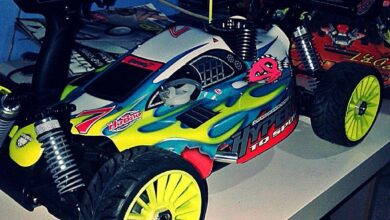 Coche de rally de radiocontrol a escala 1/8 con carroceria amarilla y verde y neumaticos de tacos, visto de tres cuartos