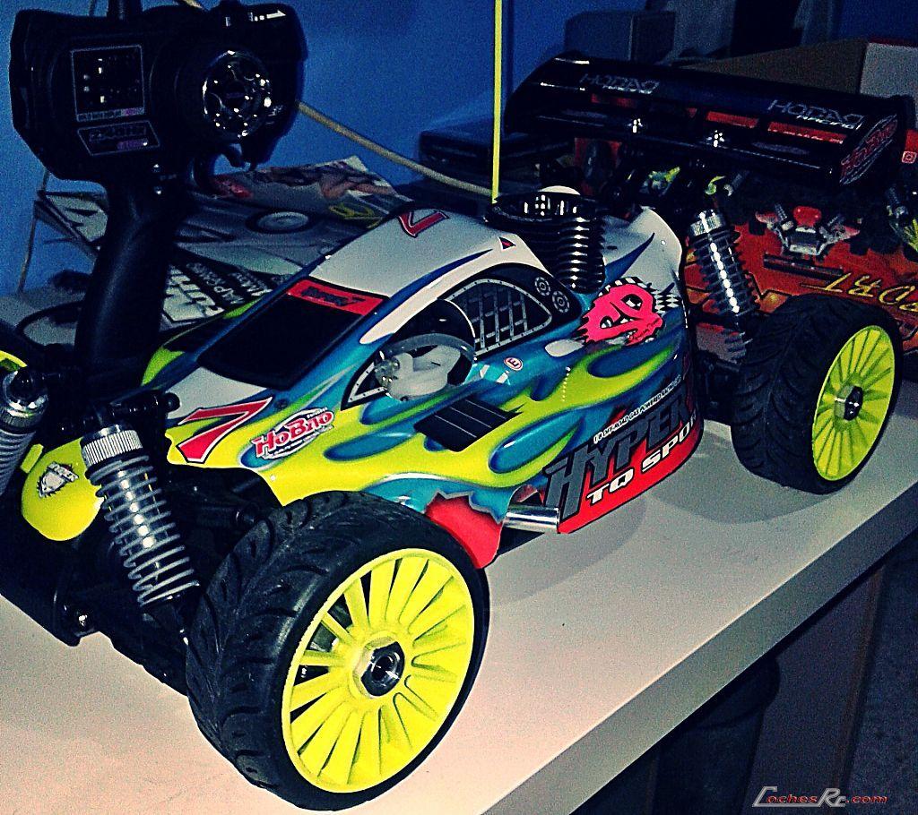 Coche de rally de radiocontrol a escala 1/8 con carroceria amarilla y verde y neumaticos de tacos, visto de tres cuartos