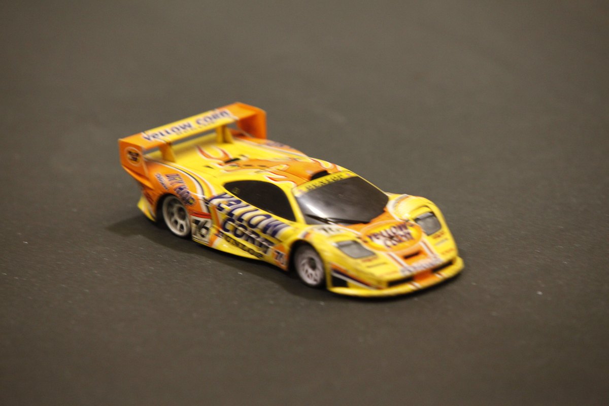 Coche de radiocontrol de escala pequena rodando en una pista de interior