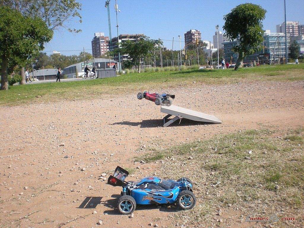 Buggy de radiocontrol todo terreno en el aire tras saltar una rampa de madera sobre un terreno de tierra