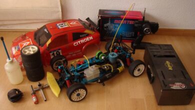 Dos coches de radiocontrol de rally con su emisora, botes de combustible y herramientas