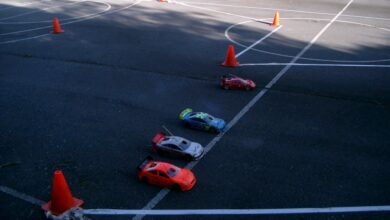 Varios coches RC de touring rodando sobre una pista de asfalto con conos