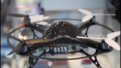 Dron cuadricoptero de radiocontrol visto de frente, con sus cuatro brazos, helices blancas y la electronica a la vista