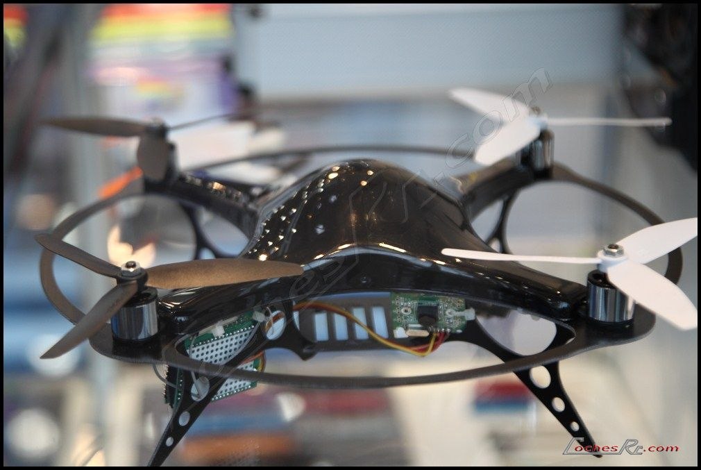 Dron cuadricoptero de radiocontrol visto de frente, con sus cuatro brazos, helices blancas y la electronica a la vista