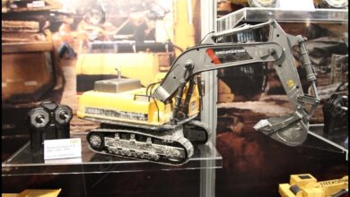 Excavadora de radiocontrol a escala con orugas de cadenas y brazo articulado con cazo, expuesta en una vitrina
