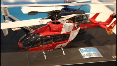 Helicoptero de radiocontrol a escala con carroceria roja y blanca de helicoptero de rescate, expuesto sobre una peana
