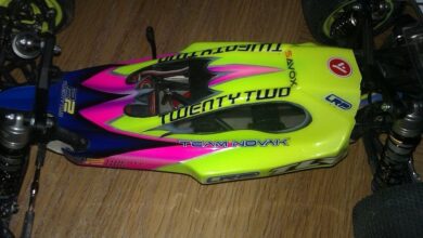 Buggy electrico de competicion Team Losi Racing 22 con carroceria rosa y verde vista desde arriba sobre suelo de madera