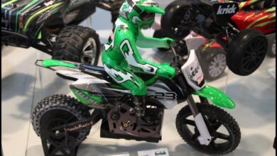 Moto de motocross de radiocontrol con carenado verde y blanco apoyada en su soporte de exposicion