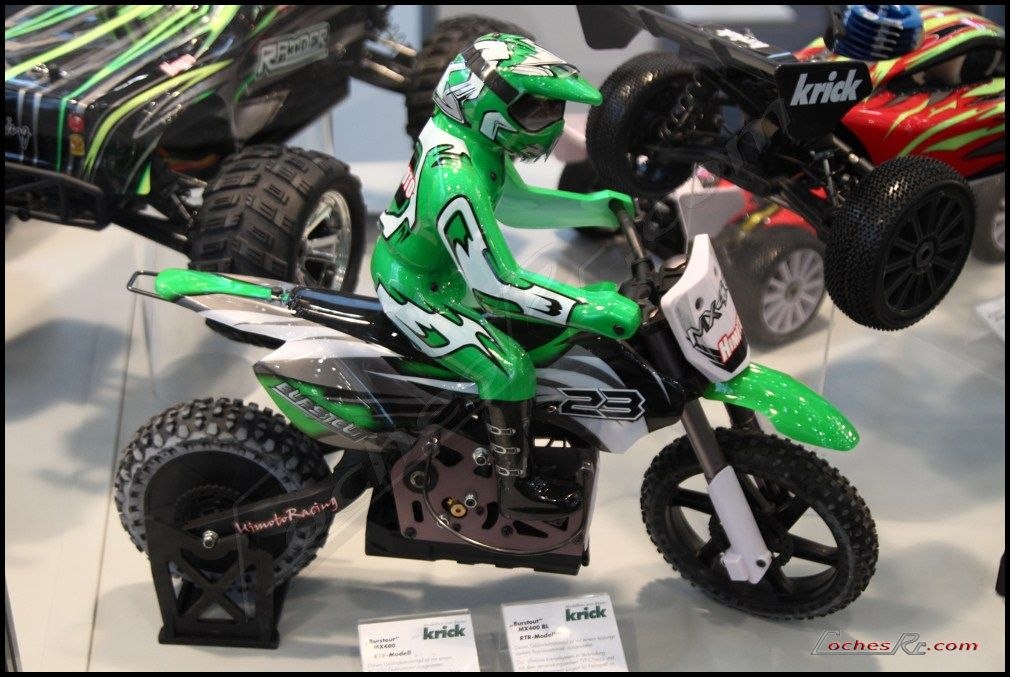 Moto de motocross de radiocontrol con carenado verde y blanco apoyada en su soporte de exposicion