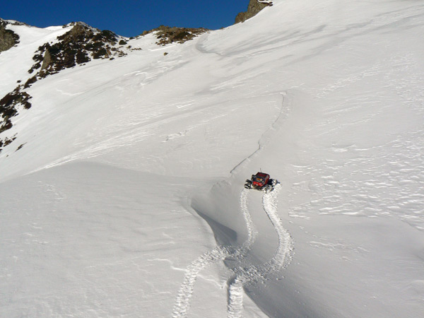 Coche de radiocontrol subiendo una ladera nevada, con el rastro de sus rodadas marcado en la nieve