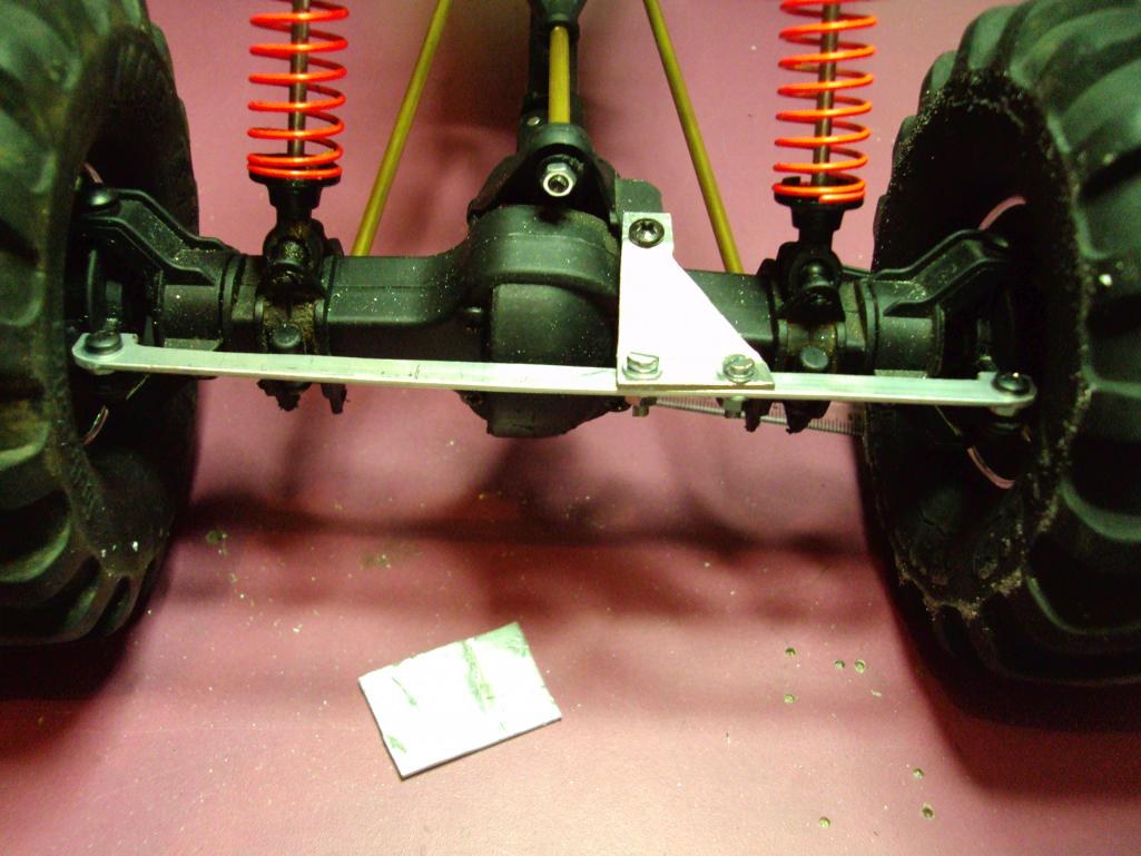 Eje trasero de un crawler con un soporte de plástico y una pletina de aluminio que fija los links, entre los muelles rojos