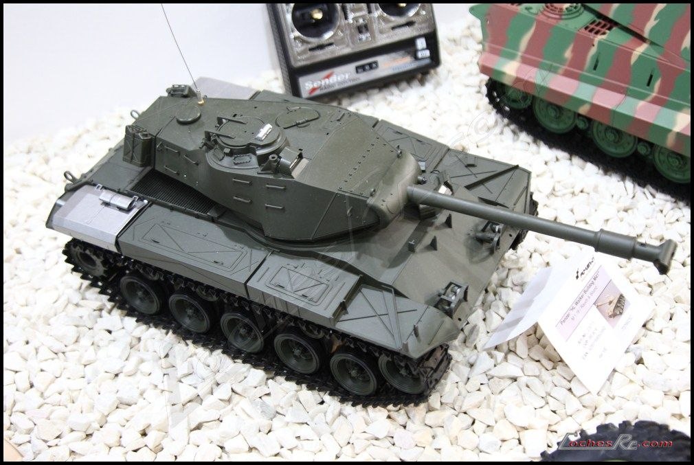 Tanque de radiocontrol a escala en color verde militar, con orugas metalicas, torreta y canon, sobre grava blanca