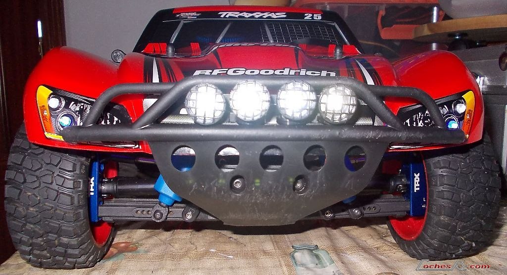 Frontal de un Traxxas Slash de short course rojo con parachoques tubular, faros y neumaticos todo terreno