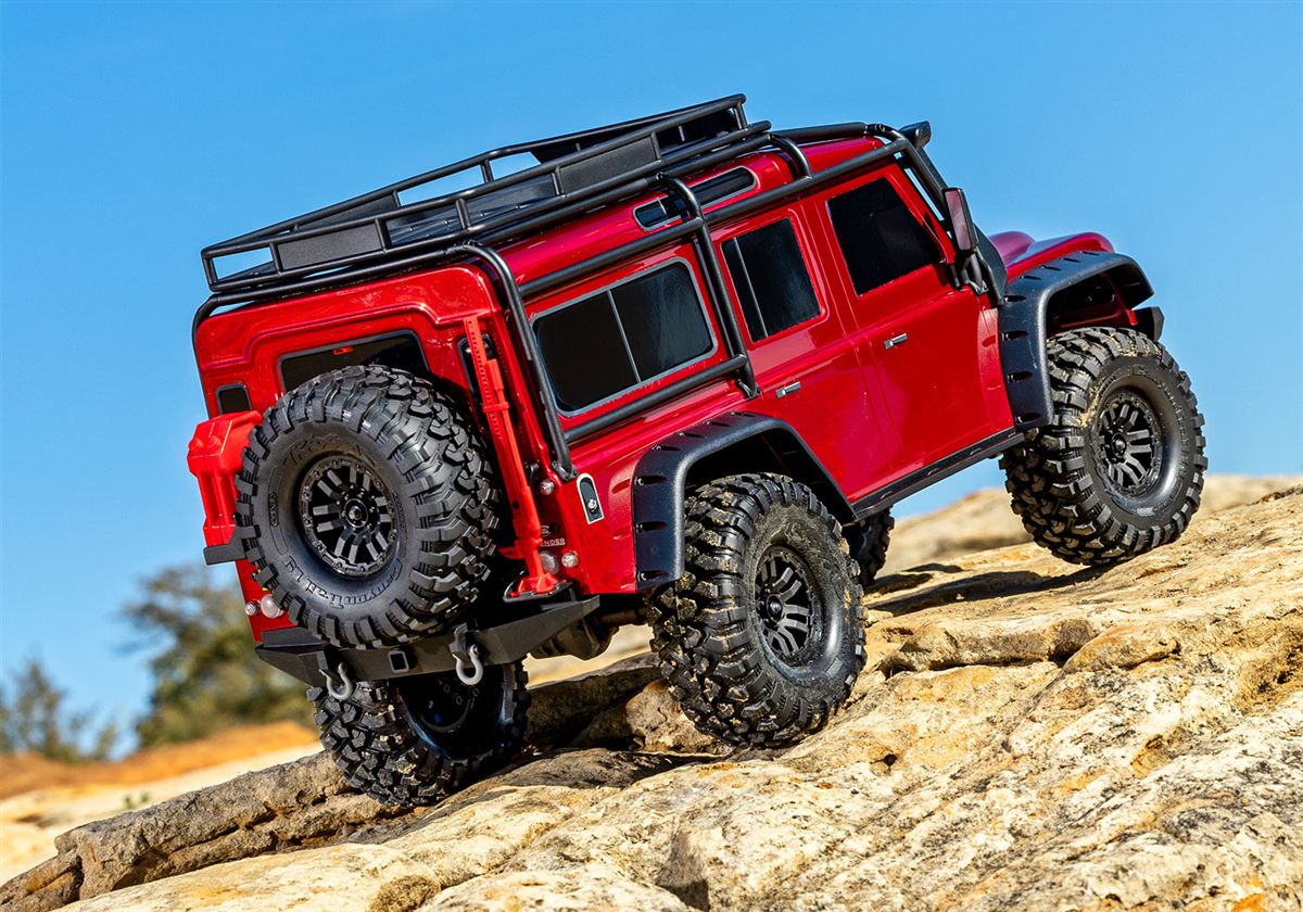 Traxxas TRX-4 con carroceria Land Rover Defender roja trepando por rocas